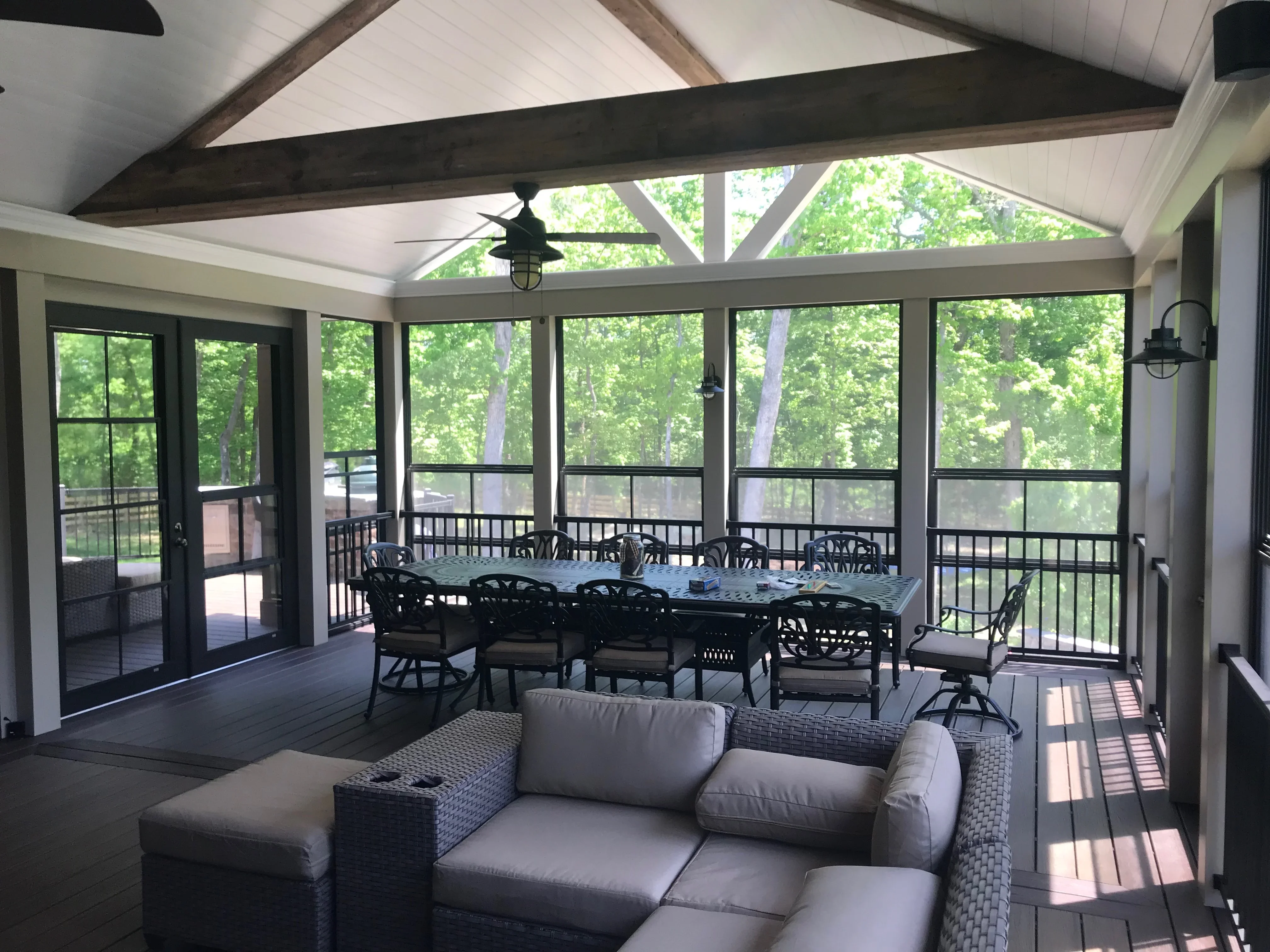 Screened patio with exposed beam ceiling, black-framed windows, composite deck, and aluminum railings